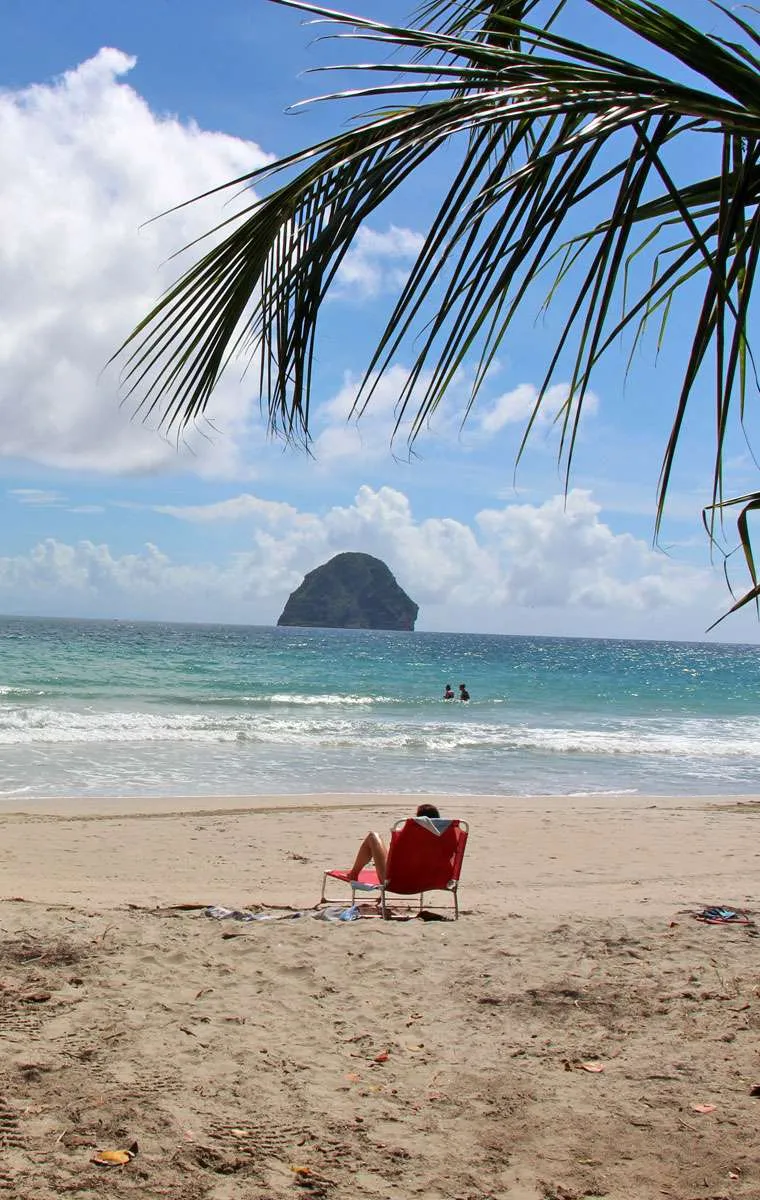 Personne sur une chaise rouge en face du Rocher du Diamant